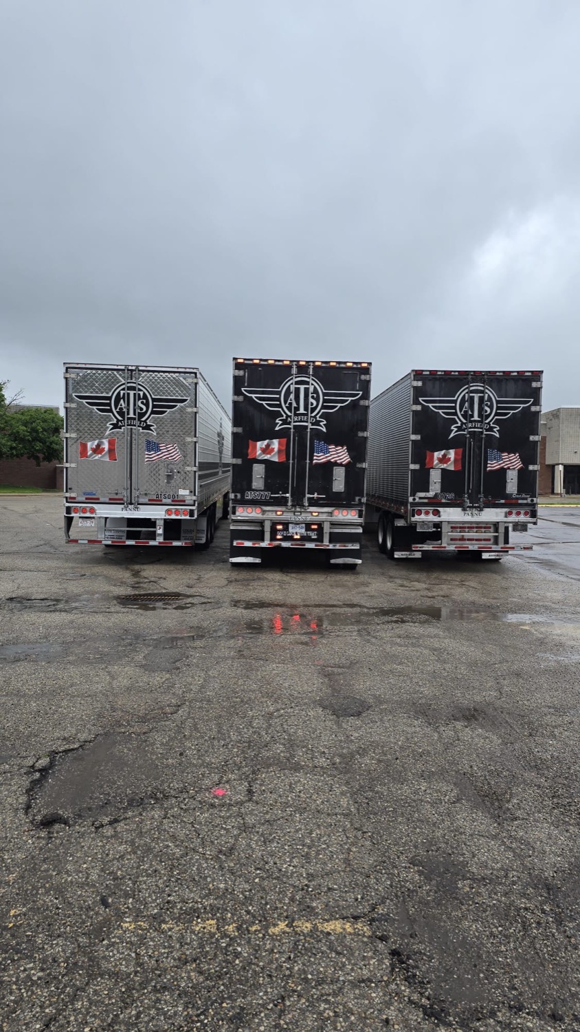 Three Airfield Trucking reefer trailers, rear view, with Canada and U.S. flag decals