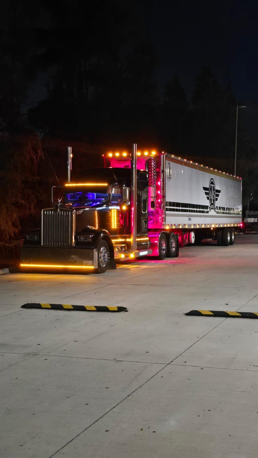Black Kenworth W900 with chrome stacks and LED accent lighting at night, pulling an Airfield reefer