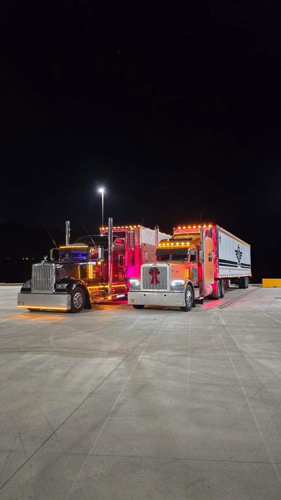 Two polished Airfield Trucking show trucks photographed at night