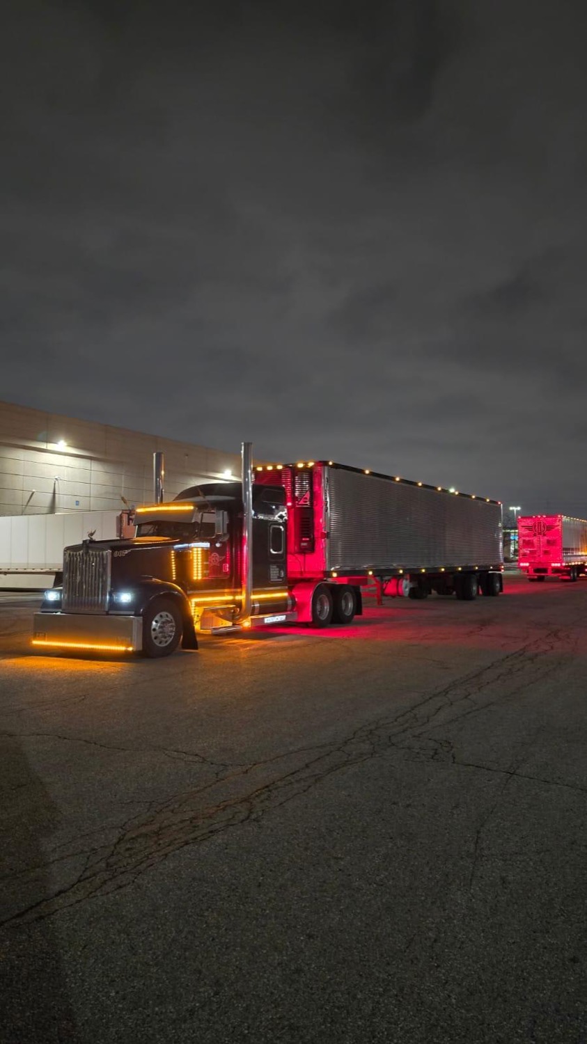 Black Kenworth W900 &ldquo;007&rdquo; with red and amber lights at a loading dock at night