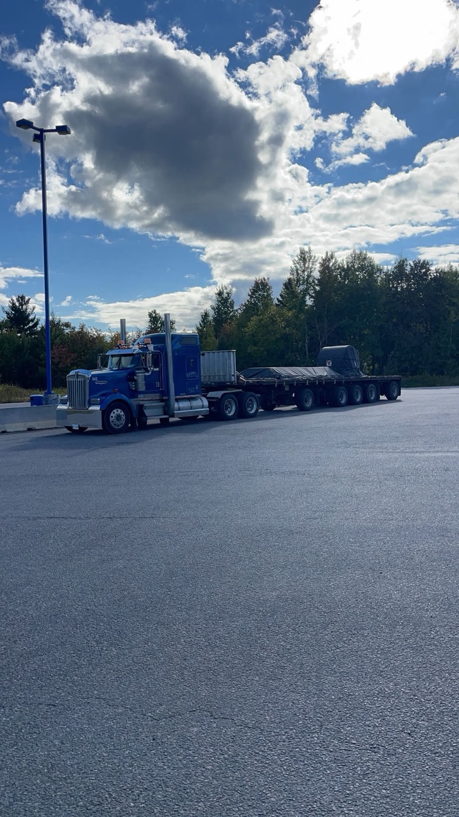 A blue Kenworth with an empty step-deck trailer showing the low deck height